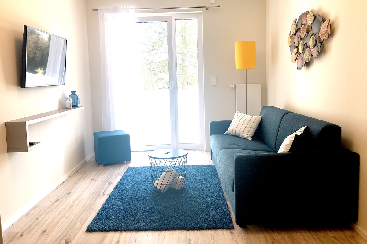 Wohnzimmer mit Fernseher und Zugang zum Balkon